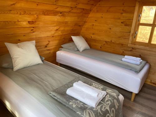 two beds in a room with wooden walls at Starlight Camping Pods in Hvolsvöllur