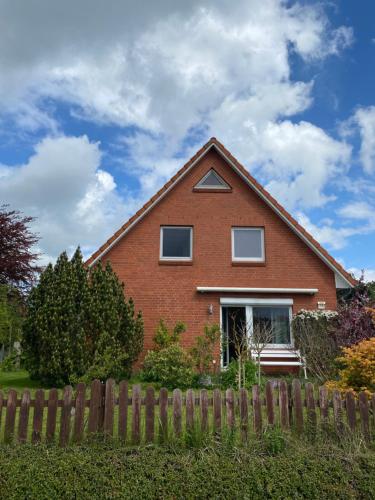 a red brick house with a wooden fence at Ferienhaus Annu in Lensahn