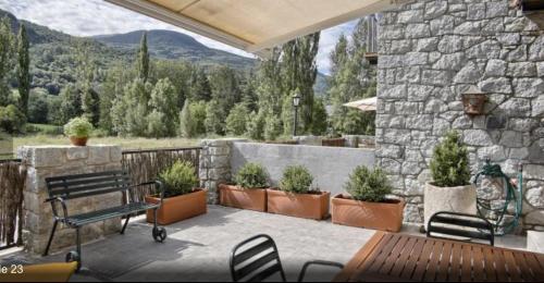 un patio avec un banc et des plantes en pot ainsi qu'un mur en pierre dans l'établissement Apartamento Rincon del cielo, à Benasque