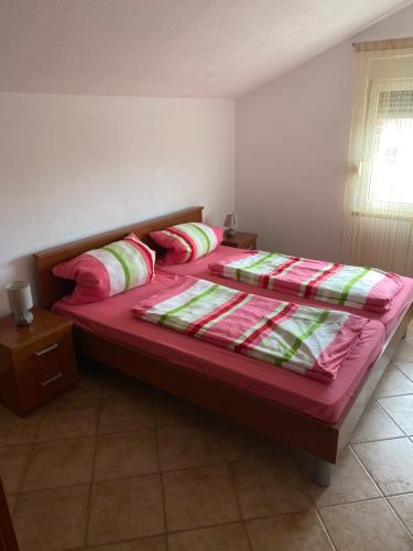 1 dormitorio con 1 cama con sábanas y almohadas rojas en Apartmani Sabljic, en Poljica