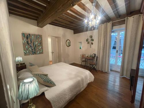 Un dormitorio con una gran cama blanca y una mesa en Fleurs de Vignes Piscine, en Montagny-lès-Beaune