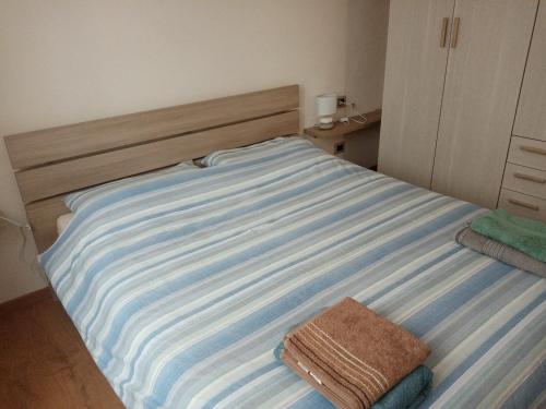 a bed with a blue and white striped sheets at Appartamento Prima Rosa in Primaluna