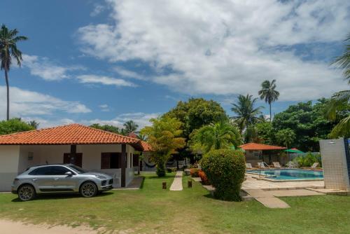 un coche aparcado frente a una casa con piscina en Village Miramar en Maragogi