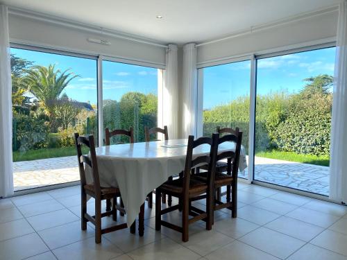 a dining room with a table and chairs and large windows at REF 052 Maison pour 7 personnes à proximité du Golfe du Morbihan à louer pour les vacances in Arzon
