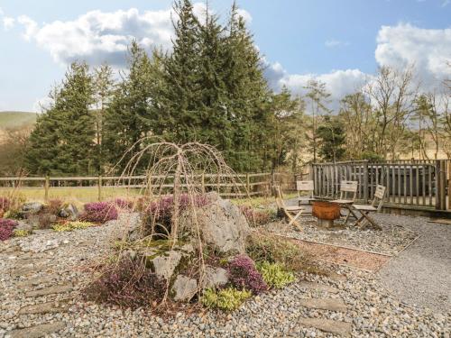 a garden with flowers and a bench and a fence at The Lodge in Merthyr Tydfil