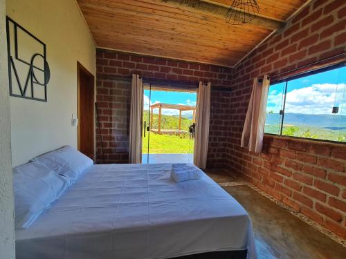a bedroom with a bed and a brick wall at Bangalô do Amor in Serra do Cipo