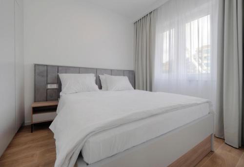 a white bed in a white bedroom with a window at Horizon Two bedroom Apartment with sea view Jake in Becici