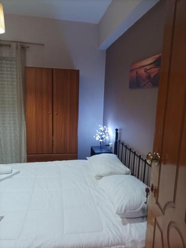 a bedroom with a large white bed with a wooden cabinet at Eirini's Apartment in Missolonghi