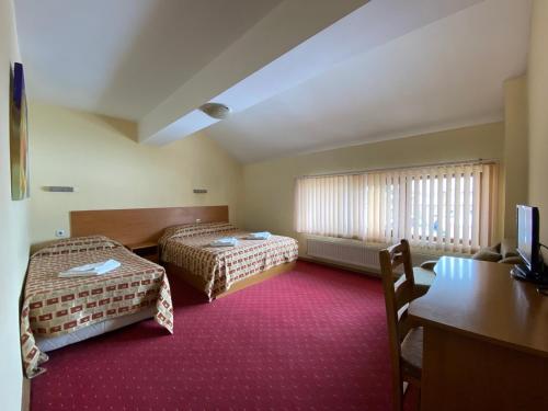 Habitación de hotel con 2 camas y escritorio en Family House Oreha, en Bansko