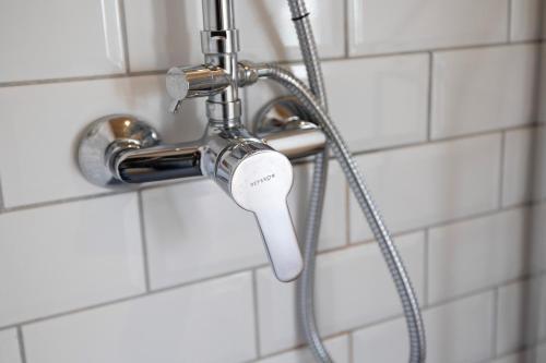a shower head in a white tiled bathroom at Pomar das Oliveiras - Private Swimming pool - Free EV Chrg - Pet Friendly in Carvalhal Cimeiro