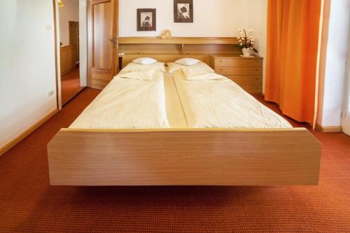 a large wooden bed in a bedroom with an orange curtain at Residence Pichler Apartment 1 in San Leonardo in Passiria