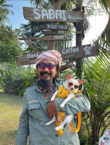 a man holding a dog in front of a street sign at Ko Yao Noi Sabai Bungalows in Ko Yao Noi