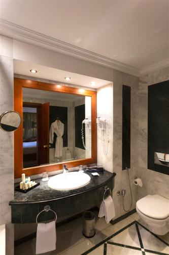 a bathroom with a sink and a toilet and a mirror at Concorde Les Berges du Lac in Tunis