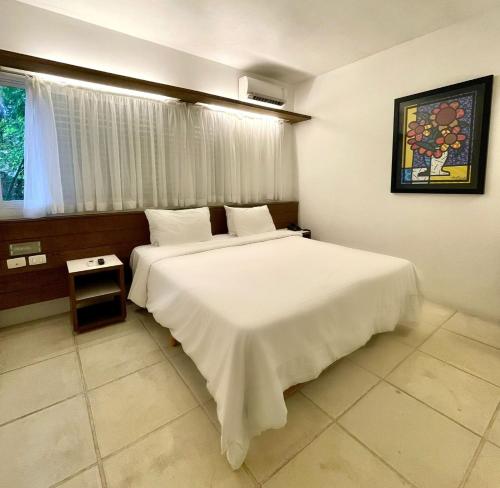 a bedroom with a large white bed and a window at Delphin Beach Hotel in Guarujá