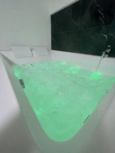 La salle de bains est pourvue d'une baignoire remplie d'eau verte. dans l'établissement Le Golf Balnéo - Cosy & SPA - Appartement, à Saint-Étienne