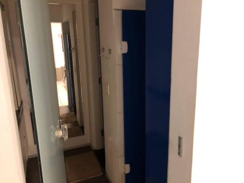 un pasillo con una puerta azul y un espejo en iHOSTEL ALDEOTA, en Fortaleza