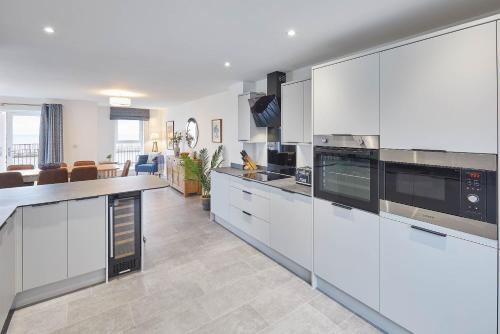 a kitchen with white cabinets and a living room at Host & Stay - 3 Queens Court in Whitley Bay
