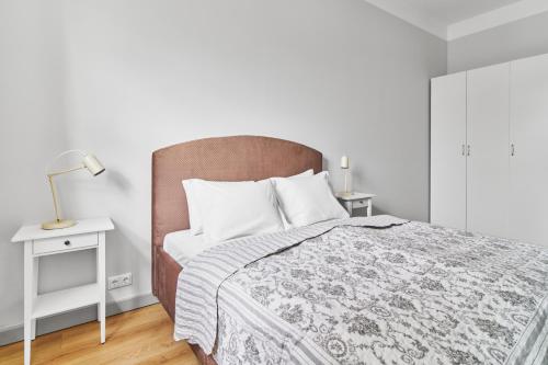 Un dormitorio blanco con una cama y una lámpara en una mesa. en New and Lovely Apartament in Vilnius City Centre en Vilna