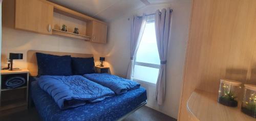 ein Schlafzimmer mit einem blauen Bett und einem Fenster in der Unterkunft Beach Resort Kamperland - 153 in Kamperland