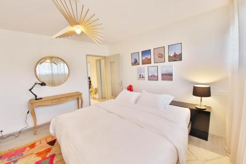 a white bedroom with a large bed and a mirror at La Maison de Jeanne in Sélestat