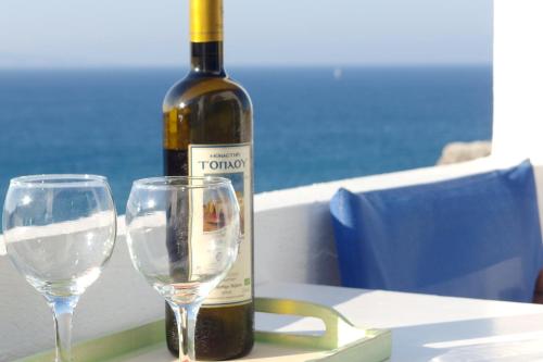 a bottle of wine and two wine glasses on a table at Ploimon Apartments in Sitia