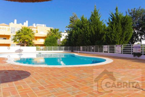 a swimming pool in the middle of a brick patio at Apartamento Margarida Royal Cabanas Golf By Your Home Algarve in Tavira