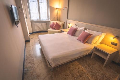 a bedroom with a white bed with pillows and a chair at Hotel Lis in Asti