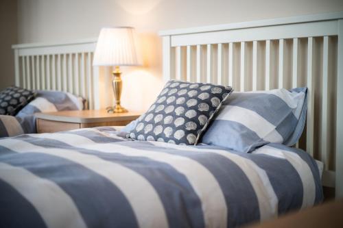 a bed with a blue and white blanket and pillows at Tudor Villas Apartment, Cromer in Cromer