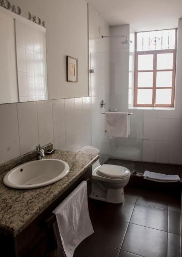 a white bathroom with a sink and a toilet at La Casa de Manuel Hotel-Boutique in Loja