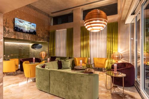 a lobby with a green couch and yellow chairs at Hotel Ariston in Milan
