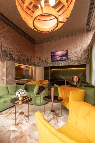 a living room with yellow and green furniture and a chandelier at Hotel Ariston in Milan