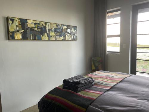 a bedroom with a bed with a painting on the wall at Lekkerberg in Riebeek-Kasteel