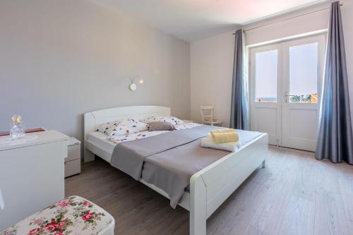 ein weißes Schlafzimmer mit einem Bett und einem Fenster in der Unterkunft House Milenka in Banjol