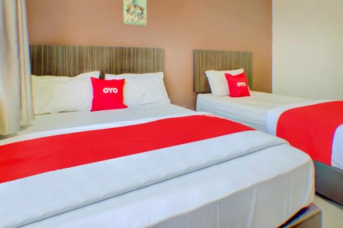 Duas camas num quarto com almofadas vermelhas e brancas em Super OYO 89985 Js Hotel em Johor Bahru