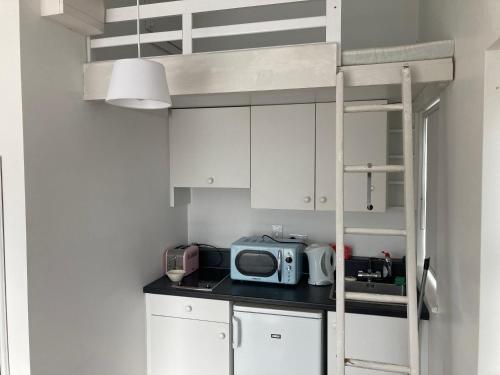 a small kitchen with white cabinets and a bunk bed at Sandy Cove in Dunmore East