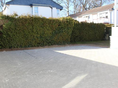 a hedge in front of a house with a driveway at Hotel Sonnenklause in Travemünde