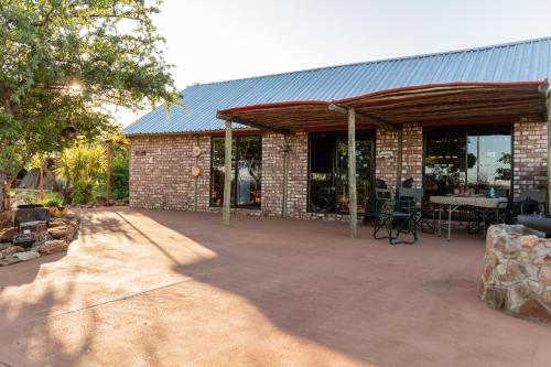 a brick building with a metal roof and a patio at Tana Safaris Bush Camp in Otjiwarongo