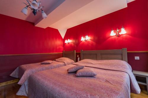 two beds in a red bedroom with red walls at Hôtel De Calais in Le Tréport