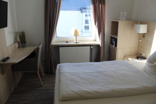 a bedroom with a bed and a desk and a window at Hotel Sonnenklause in Travemünde
