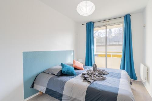 a bedroom with a bed with blue curtains and a window at Appart'Hotel Versailles Saint Cyr l'Ecole - Gare SNCF RER in Saint-Cyr-lʼÉcole