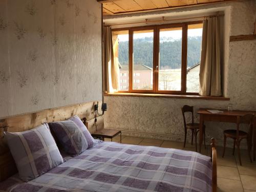 a bedroom with a bed and a window and a table at Hôtel Von Bergen in La Sagne