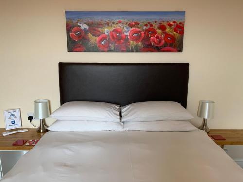 ヘレフォードにあるBouvrie Guest Houseのベッドルーム1室(赤いポピーの絵画が飾られたベッド1台付)
