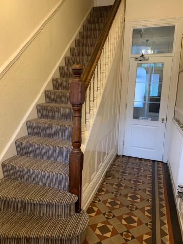 a hallway with a staircase with a carpet and a door at Bouvrie Guest House in Hereford