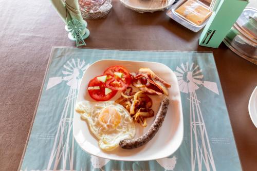 a plate of food with a sausage and tomatoes on a table at Tana Safaris Bush Camp in Otjiwarongo