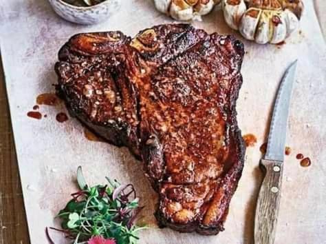a steak on a cutting board with a knife at Balule Bushveld Safari Lodge in Phalaborwa