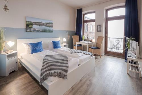a bedroom with a large white bed with blue pillows at Gästehaus Von Herzen in Lauenburg