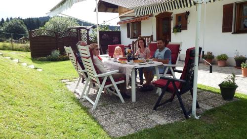 a group of people sitting around a table in a yard at Haus Bergblick in Lindberg