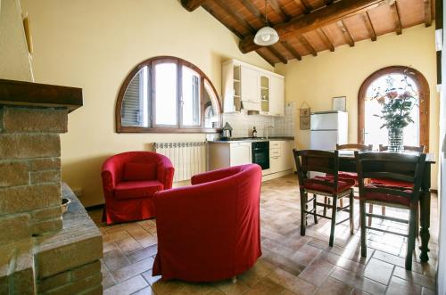 a kitchen and dining room with red chairs and a table at Le Fonti A San Giorgio in Montespertoli