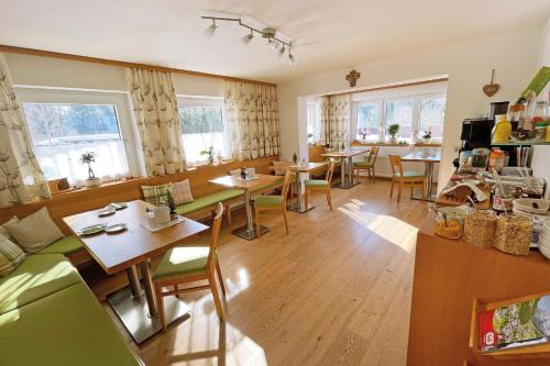 a living room with tables and chairs and windows at B&B Landhaus Vierthaler in Filzmoos