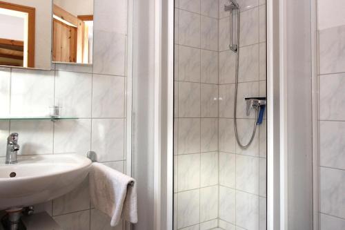 ein weißes Bad mit einem Waschbecken und einer Dusche in der Unterkunft Am Prerowstrom in Prerow